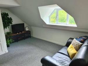 a living room with a leather couch and a window at Park House Self-Contained Annex in Mold
