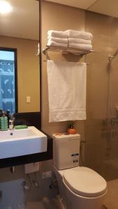 a bathroom with a toilet and a sink and towels at New Paradise Ocean View Apartment (DOT accredited) in Boracay