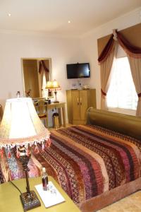 a hotel room with a bed and a lamp on a table at The Angels Place Boutique Guest House in Pretoria