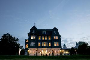 a large black house with its lights on at Hotel & Café Daheim in Masserberg