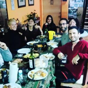 grupa ludzi siedzących przy stole z jedzeniem w obiekcie HOSTEL JUJUY w mieście San Salvador de Jujuy