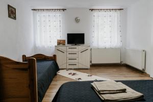 um quarto com duas camas e uma televisão numa cómoda em La Conac 13 Ceasuri Bune em Bran