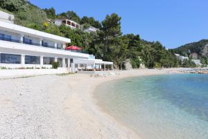 ein Strand mit einem Gebäude und dem Wasser in der Unterkunft Apartments by the sea Zivogosce - Porat, Makarska - 18218 in Igrane