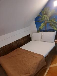 a bed in a room with a palm tree painting on the wall at APARTMANI MIA VUKSANOVIC in Cetinje