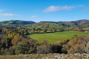 a green field with trees and mountains in the background at Park House Self-Contained Annex in Mold