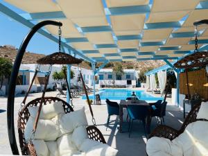 a patio with chairs and a table and a pool at Family Villages Santorini in Vlychada Beach