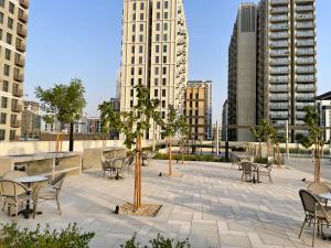 a patio with tables and chairs in a city at Dubai Hills Estate Deluxe 2 bedroom Apartment Collective Tower A 603 in Dubai