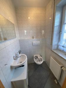 a white bathroom with a sink and a toilet at Ferienhaus Kutzenhausen in Kutzenhausen