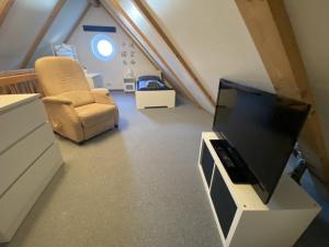 a living room with a tv and a chair at Ferienhaus Kutzenhausen in Kutzenhausen