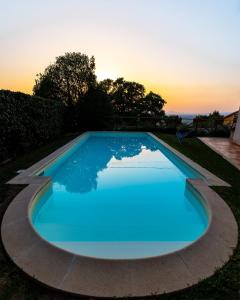 a blue swimming pool with a sunset in the background at Albergo Ristorante Il Terziere in Trevi