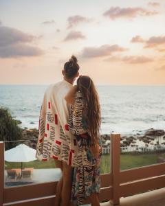 Ein Mann und eine Frau stehen auf einem Balkon mit Meerblick in der Unterkunft Belika Beach Club in Hiriketiya