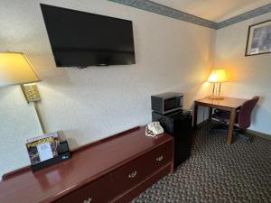 ein Hotelzimmer mit einem TV und einem Schreibtisch mit einem Bett in der Unterkunft Americas Inn Bardstown in Bardstown