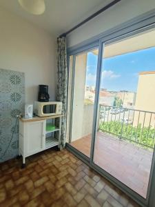 pokój z drzwiami otwartymi na balkon z kuchenką mikrofalową w obiekcie Appartement pour 4 personnes à 50m de la plage Narbonne Plage 4LP2A8 w mieście Narbonne-Plage