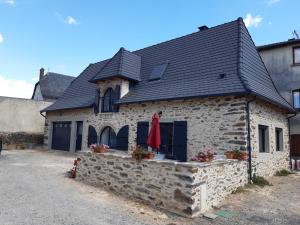 una antigua casa de piedra con techo negro en gite de La Carrière, en Saint-Julien-de-Piganiol