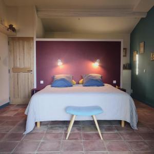 a bedroom with a large bed and a blue stool at chambre d'hôtes Et Puis Voilà! in Murs