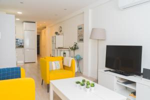 ein Wohnzimmer mit gelben Stühlen und einem TV in der Unterkunft Precioso Apartamento 2 hab. en Malaga Centro in Málaga