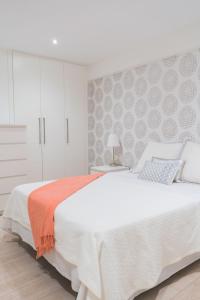 ein weißes Schlafzimmer mit einem großen Bett und einer Wand in der Unterkunft Precioso Apartamento 2 hab. en Malaga Centro in Málaga