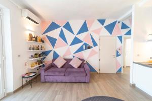a living room with a purple couch and a geometric wall at Boutique Apartment in Chiusi