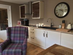 una cocina con fregadero y un reloj en la pared en Brewer's Cottage - Brosterfield Farm en Eyam