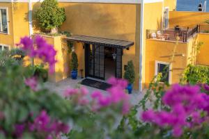 a yellow building with a black door and flowers at Casa Nonna Bodrum - Adult Only in Bodrum City