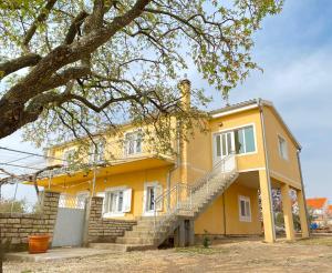 una casa amarilla con escaleras delante en Apartment Kantun, en Skradin