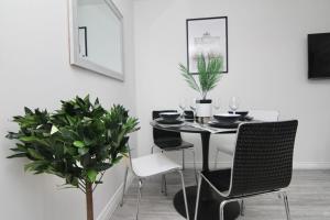 a dining room with a black table and chairs at Dashing 2Bed Haven - Near Coventry Centre, Free Parking in Coventry