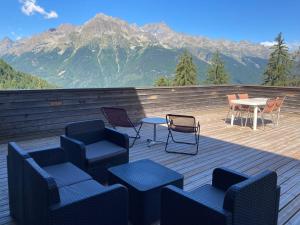 una terraza con sillas y mesas con montañas en el fondo en Timberlodge en Oz