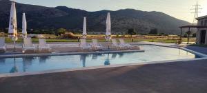 a swimming pool with chairs and umbrellas on it at Petrina Bolosis 