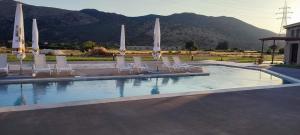 a swimming pool with chairs and umbrellas on it at Petrina Bolosis in Palaiókastron