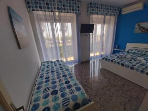 a bedroom with two beds and a tv and two windows at Blue Dream in Gaeta