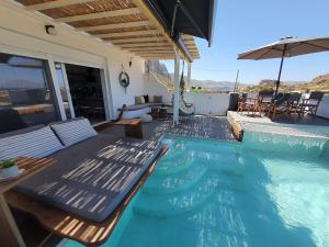 a pool with chairs and an umbrella on a house at Tramonto Luxury Villa No2 - Breathtaking sunset view in Karpathos Town