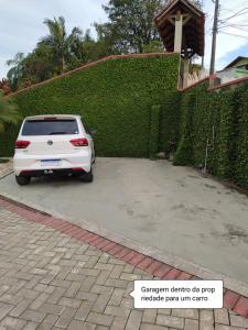 a white car parked in a driveway next to a green hedge at Quarto Inteiro Privado - 3km Oktoberfest in Blumenau