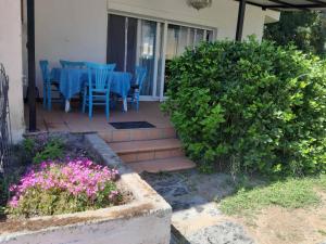 a patio with blue chairs and a table and flowers at Palio Villa in Paleo Tsifliki
