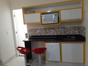 a kitchen with two red stools and a microwave at Caldas Novas Lacqua Di Roma IV - 2 banheiros e cozinha, piscina 24 horas in Caldas Novas