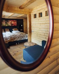 a mirror reflecting a bedroom with a bed and a stool at Alpen Lodge Berwang in Berwang