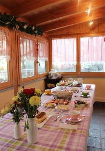 een lange tafel met eten en bloemen in een kamer bij B&B Chez Annie in Donnaz