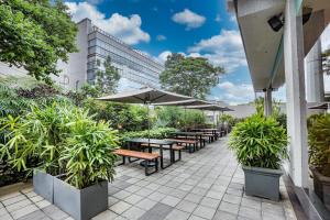 an outdoor patio with tables and umbrellas and plants at The Sulit Whitefield in Bengaluru