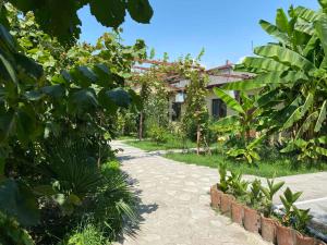 un camino en un jardín con una casa en el fondo en Hotel Villa Eniseli en Eniseli