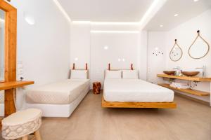 two beds in a room with white walls and wooden floors at Hotel Thira in Fira