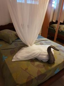 a bed with a white sheet and a stuffed snake on it at Label kafé in Bouillante