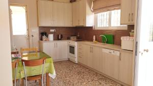 a kitchen with white cabinets and a table with a green table cloth at Anastasia's House near Kalamata in Dhesíllas