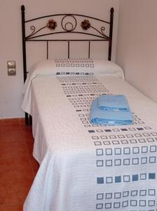 a bed with a white bedspread with a blue towel on it at Casa Yaya Felisa in Lledó