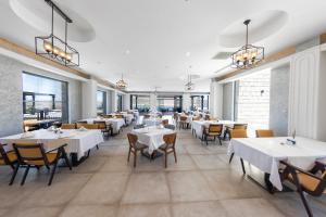 un restaurante con mesas y sillas blancas y ventanas en Soliport Hotel & SPA en Alacati