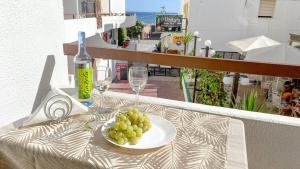 a plate of grapes on a table with a bottle and glasses at Magnífico apartamento a 35m da praia - Apart. Isa in Albufeira