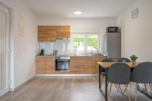 una cocina con armarios de madera, mesa y sillas en Apartmani Villa Ruby, en Linardići