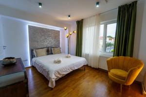 een slaapkamer met een bed, een stoel en een raam bij Main square 5 star luxury apartment with view in Cluj-Napoca