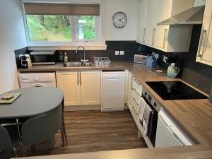 a kitchen with white cabinets and a sink and a table at Loch Eyre Cottage in Kensaleyre