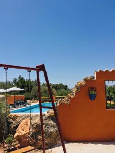 uma piscina com um baloiço ao lado de uma casa em Casa rural Antonio y Esperanza em Periana