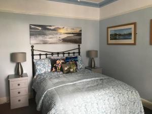 a bedroom with a bed and two lamps and a painting at Craig-y-Mor in Criccieth