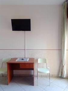 拉戈內格羅的住宿－Hotel Caimo Bed-Breakfast，一张桌子、椅子和墙上的电视